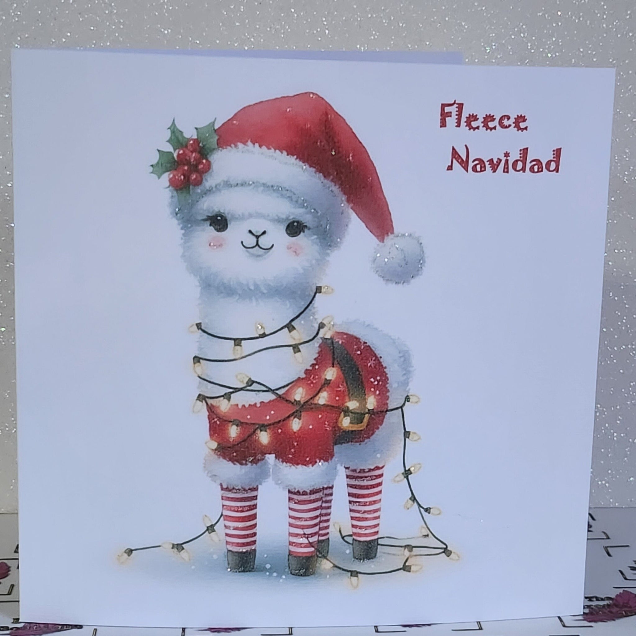 Feliz Navidad Llama Christmas Card ' Fleece Navidad' Llama In Santa Hat And Christmas Lights Glitter Detailing Linen Effect Free Delivery