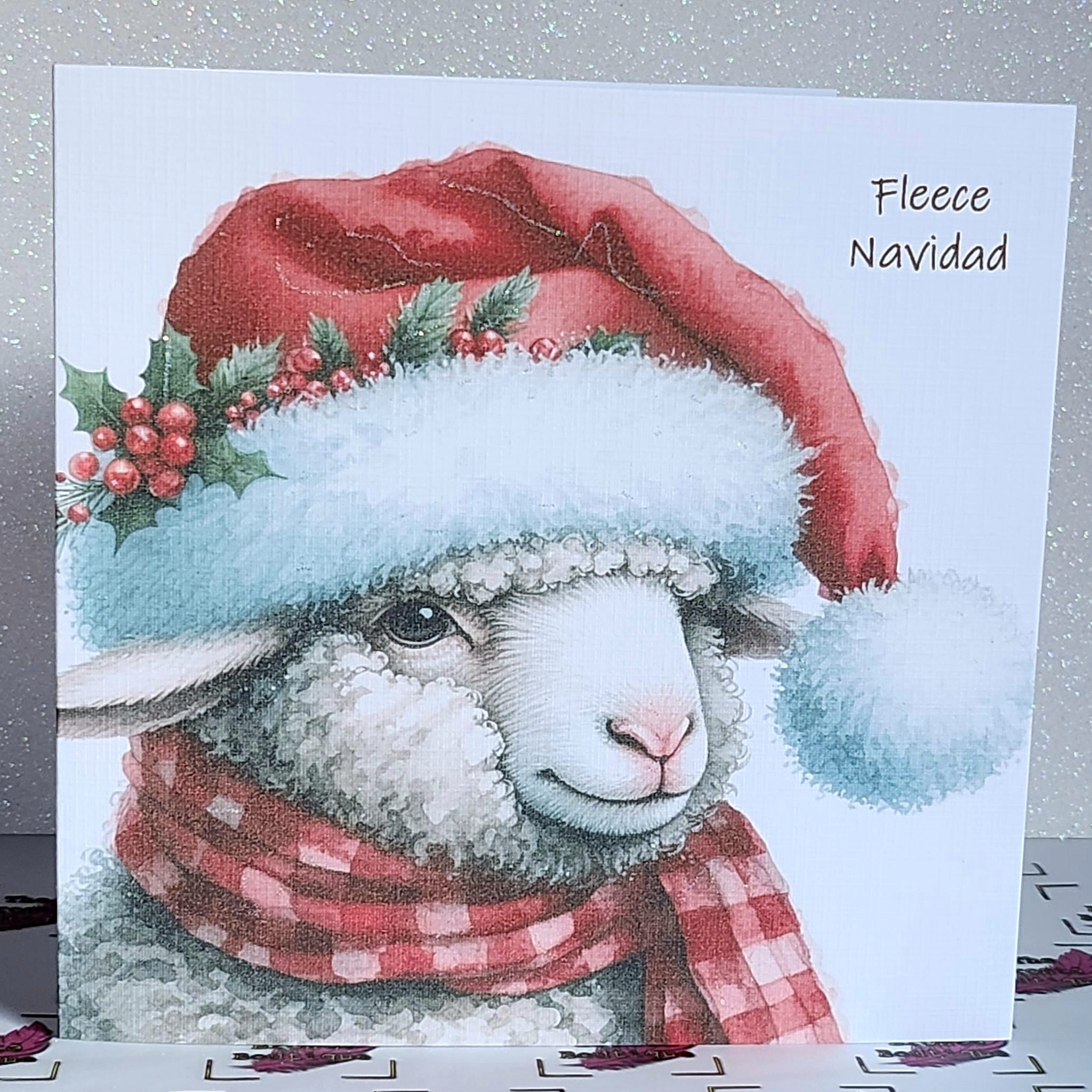 Feliz Navidad Sheep Christmas Card ' Fleece Navidad' Sheep In Santa Hat With Holly And Scarf Glitter Detailing Linen Effect Free Delivery